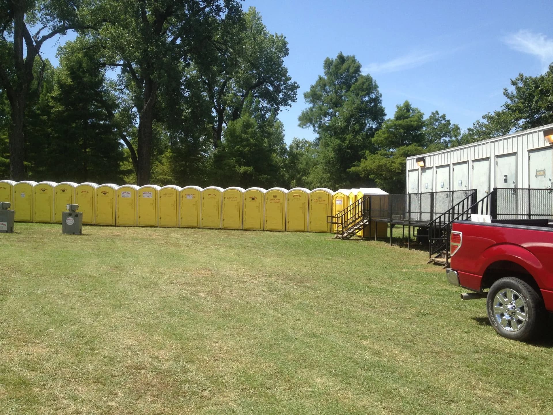 Yellow portable toilets set beside an industrial building on an Oklahoma site