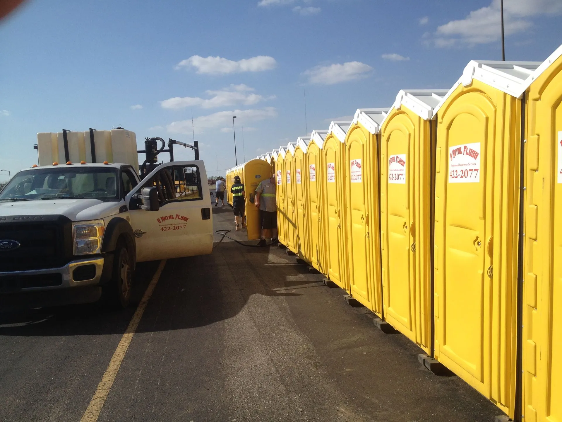 A Royal Flush truck delivering a row of yellow portable toilets to a job site