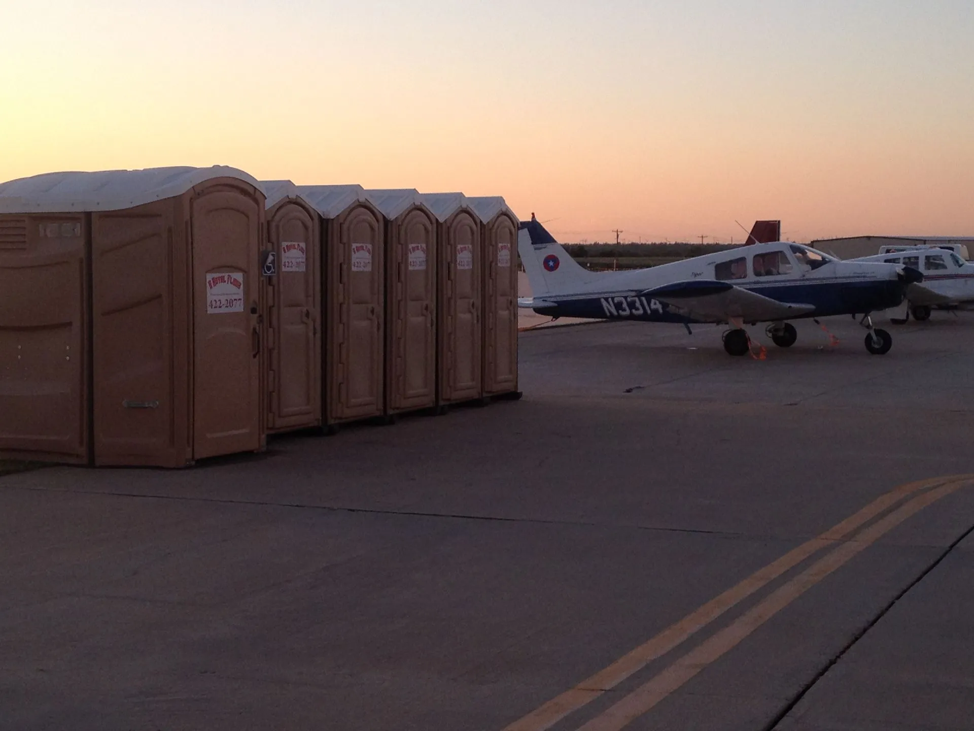 Portable toilets staged at an airfield event at dusk