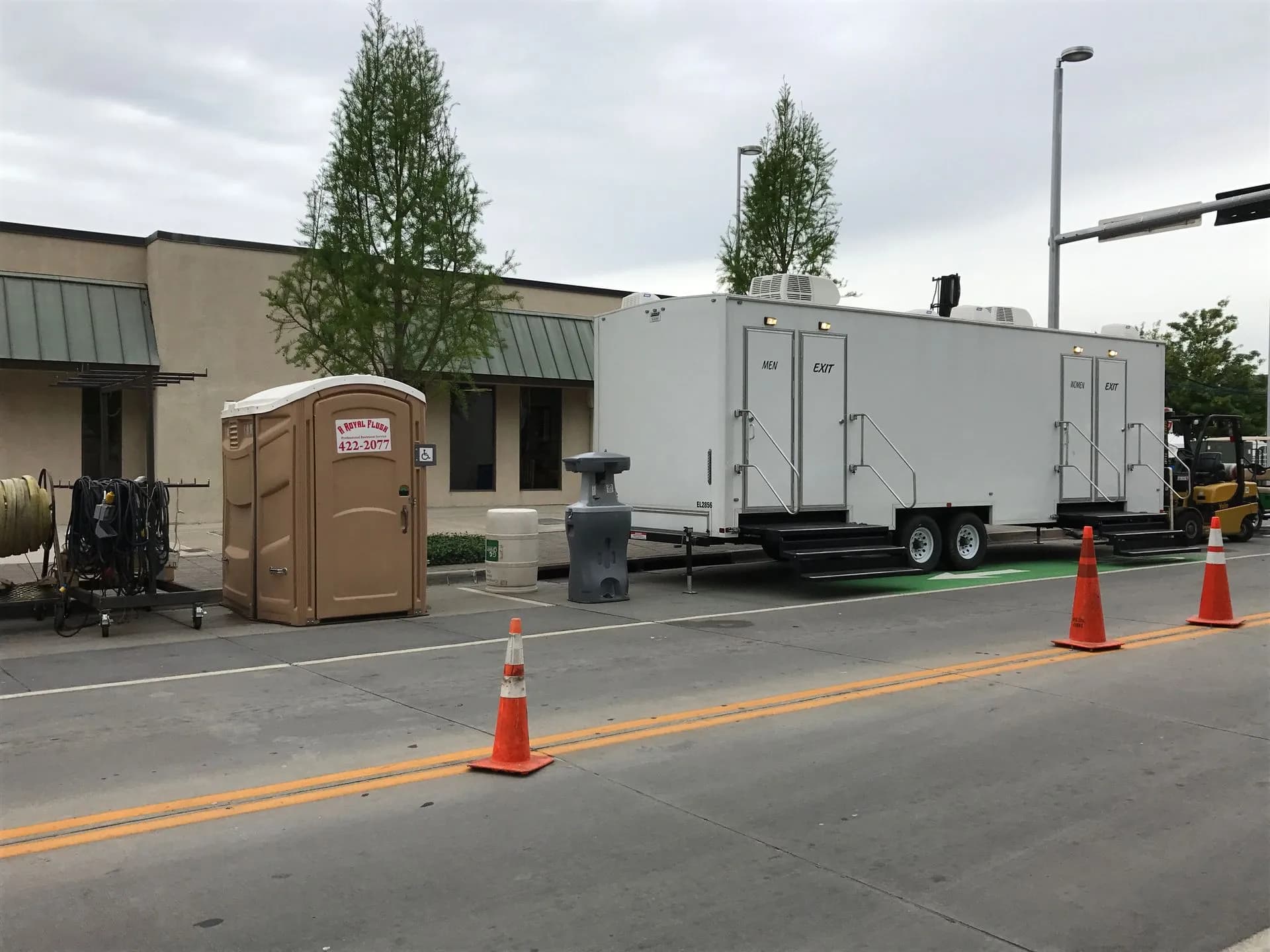 Portable restroom with a free-standing handwash station beside a restroom trailer